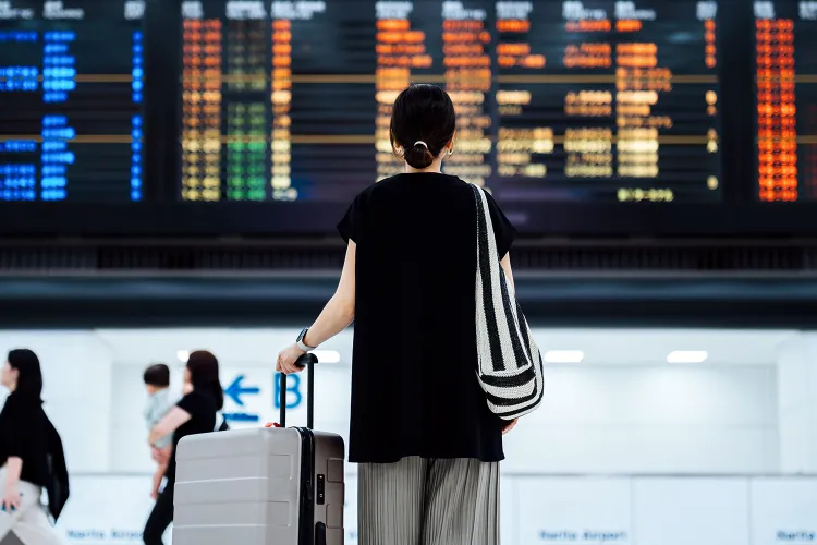 woman standing in front of departure board 080626 e8af0a6a354e40ab84c1350a48d792de